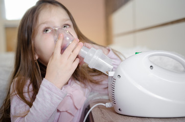 Cute little baby in the mask of an inhaler. Procedure of inhalation at home. Baby taking...