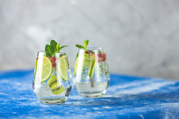 Detox water or martini tonic cocktail with kiwi, lime and ice, decoration pomegranate and mint. Summer fresh lime soda cocktail, selective focus