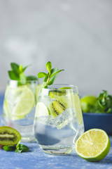 Two detox water, mojito or martini tonic cocktail with kiwi, lime, ice, mint. Summer fresh lime soda cocktail, selective focus. A new kind of mojito with kiwi, lime and mint and of course ice