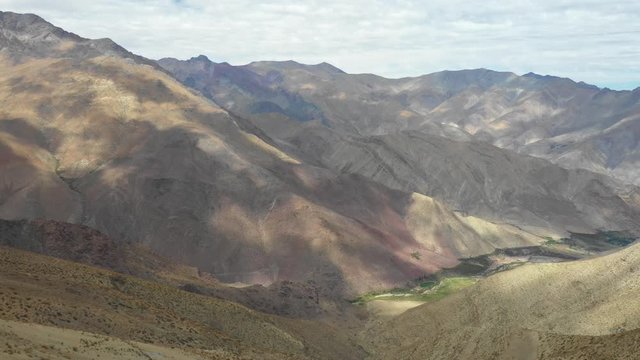 An aerial view inside Andes mountains at Limari Valley, south Atacama. An amazing wild scenery. Arid idyllic valleys with green farm fields feed in by the river at the bottom of the valley
