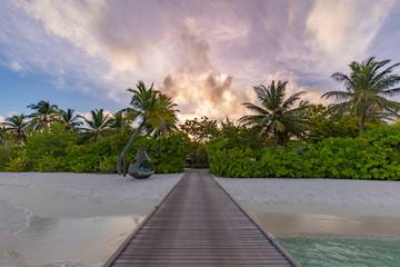 Sunset on Maldives island, luxury water villas resort and wooden pier. Beautiful sky and clouds and...