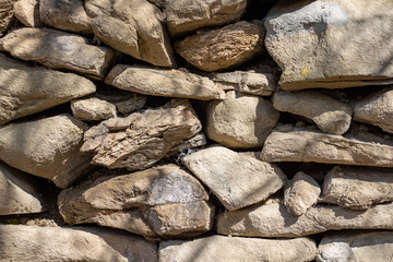 Stone fence wall, stone house. Hard slate slab rock texture, natural narrow brick, beige, yellow, gray