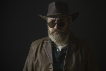Sexy cowboy in a hat on the dark background.