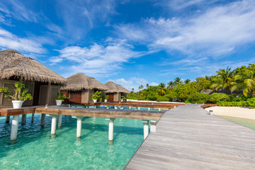 Exotic landscape of Maldives beach. Tropical panorama, luxury water villa resort with wooden pier or jetty. Luxury travel destination background for summer holiday and vacation concept.