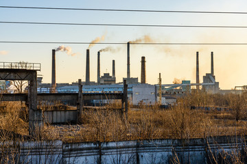 View on smoke pipes of the factory at sunset