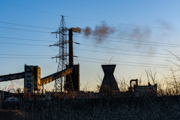 View on smoke pipes of the factory at sunset