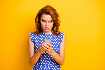 Photo of attractive foxy lady hold telephone open mouth see negative comments reaction new port followers wear polka-dot blue white shirt isolated yellow color background