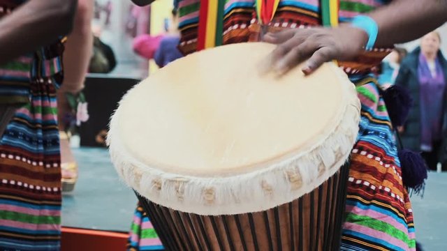 Close-up African s hands playing on djembe drum close up. Musician beats rhythm on african drums. Black artists hit the drums with their hands. Girls dancers dance samba. Brazilian carnival atmosphere