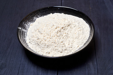 Plate with flour on a dark background.