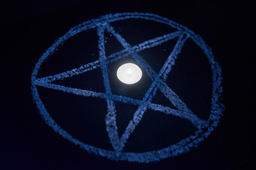 Pentagram and burning candles. The magical ritual of Satanism, invocation of spirits, spiritualistic sessions.