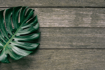 Monstera leaf top view philodendron leaf pattern on the background, old wooden table / copy space -...