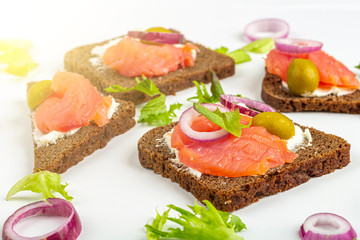 Appetizer, open sandwich with salmon and onion on white background. Traditional Italian or Scandinavian cuisine. Concept of proper nutrition and healthy eating. Close up, copy space for text