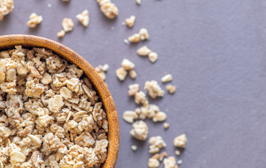 Bowl of granola close-up. Top view. Scattered granola on table surface.