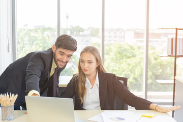 Young businesspeople working at the office with laptops and documents on their desks. With a good smile And has a beautiful orange fair