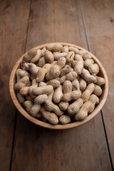 Wooden bowl of roasted peanuts in shells