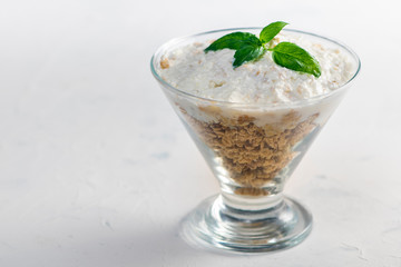 Granola in a bowl with yogurt and basil leaves. Bowl of granola on textured white table.