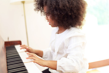 Beautiful African girl playing piano keyboard in classroom learning at room.