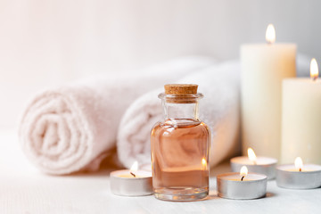 Concept of spa treatment in salon. Natural organic oil, towel, candles as decor. Atmosphere of relax, serenity and pleasure. Anti-stress and detox procedure. Luxury lifestyle. White wooden background