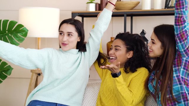 Smiling multiracial female friends taking selfie photo at home