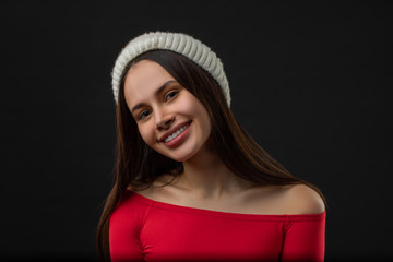 woman modern hipster portrait smiling happy and confident looking at camera on black background wearing knit hat.