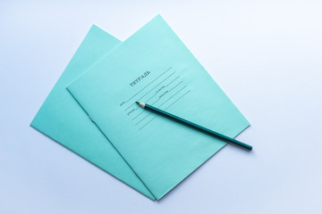Top view of two pupils copybooks with dark green pencil on white background. Concept of education, minimalism.