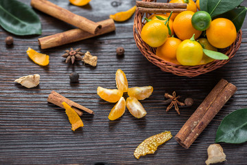 still life with calamondines in basket, cinnamon sticks, anise star, cardamom, ginger. Christmas composition on old wood. side view