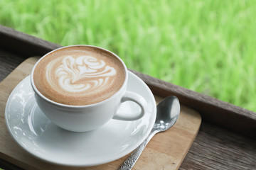 Coffee cup latte art in heart shape with a cup of dark coffee and dark chocolate on wooden table.Frothy drink for coffee break after working or weekend meeting