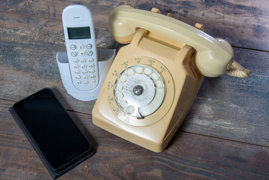 retro phone and new cell phone on wooden board