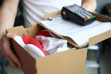 Man holds box with sneakers terminal for payment. Buyer can pay from home or in car. Postal company...