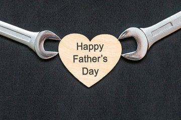 Happy fathers day concept. Mechanic wrenches spanners holding heart with Happy father's day text on...