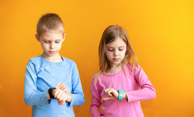 Happy children 6-8 years old with a smart GPS watch talking to parents safely. orange background