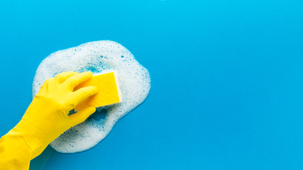 Hand wearing gloves cleaning. Blue background.
