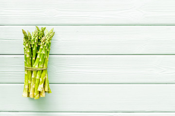 Bunch of asparagus steams on green wooden background top-down copy space