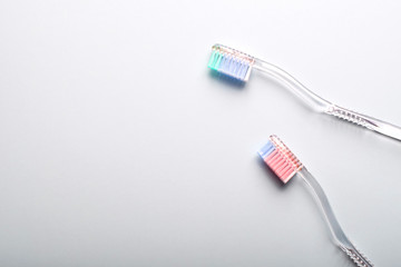 A pair of transparent toothbrushes on a grey background.