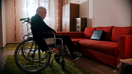 An old man sitting in a wheelchair in the room
