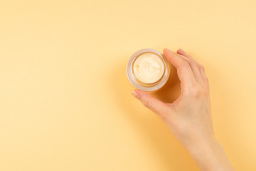 Hand cream and woman hands on a beige background.