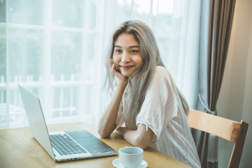 Lazy bored asian woman using laptop in the morning.