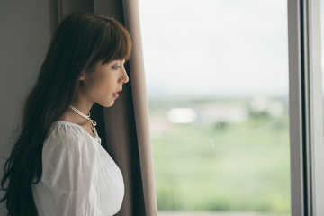 Young Woman Standing By Window At Home