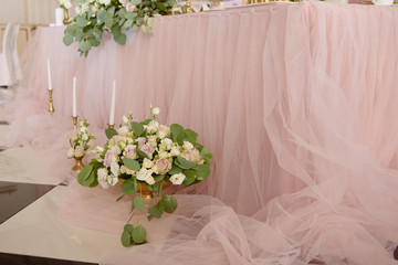 Beautiful floral arrangement of roses and greenery on the floor in restaurant, copy space. Luxury wedding decorations. Table setting