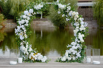 Circle wedding arch decorated with white flowers and greenery outdoors, copy space. Wedding...