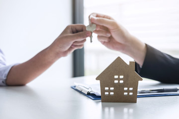 Estate agent giving house keys to client after signing agreement contract real estate with approved mortgage application form, concerning mortgage loan offer for and house insurance