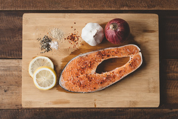 Top view of a fresh uncooked salmon on a wooden cutting board. Concept of diet menu and cooking ingredient