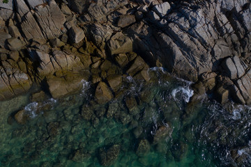 Aerial drone top view of turquoise sea surface with stones and rocks in water