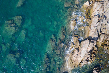 Aerial drone top view of turquoise sea surface with stones and rocks in water