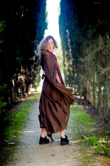 Beautiful woman with cape on a path in the woods
