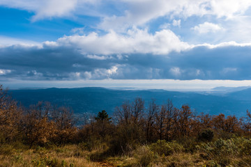 The panoramic view of Côte d'Azur Alps mountains under the cloudy sky and the Meditarrenean sea coastline in the horizon