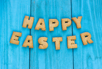 Happy Easter Creative Greeting Card or Banner. Biscuit Cookies Holiday Lettering on Blue Wooden Background.