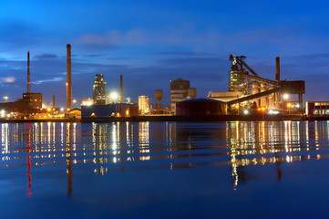 scenic night view of the steel factory in Bremen (Germany) during blue hour at dawn from the opposite side of the river Weser