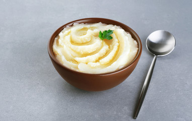 Mashed potatoes with butter and parsley on gray texture.