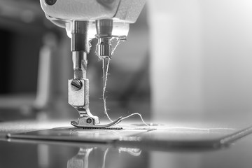 Needle of industrial sewing machine use sew cloth black and white tone (monochrome) close-up.
